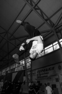 An athlete performs an acrobatic flip indoors, demonstrating skill and agility.
