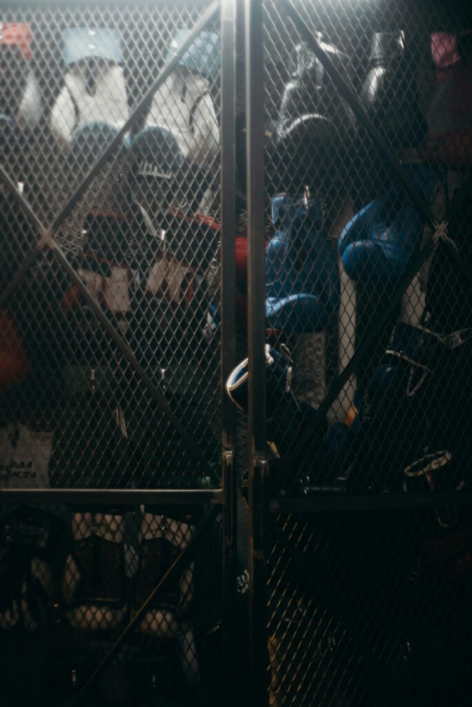 A dimly lit locker containing boxing gear including gloves and helmets in a gym setting.